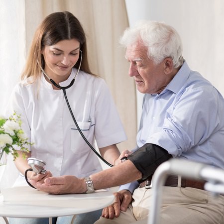 Young Nurse Taking Elderly Man's Vital Signs