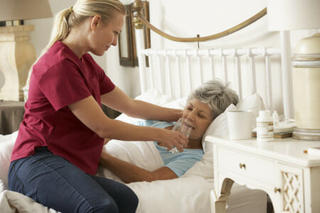 Nurse Helping Senior Patient with Water in Bed