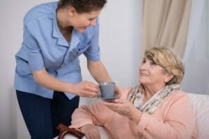 Caregiver Serving Tea to Elderly Woman