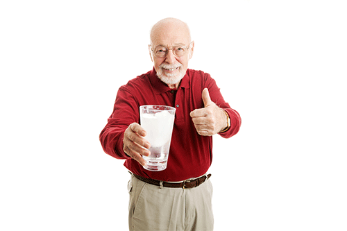 A senior man holding a glass of ice water - hydration is very important in the Arizona summer!