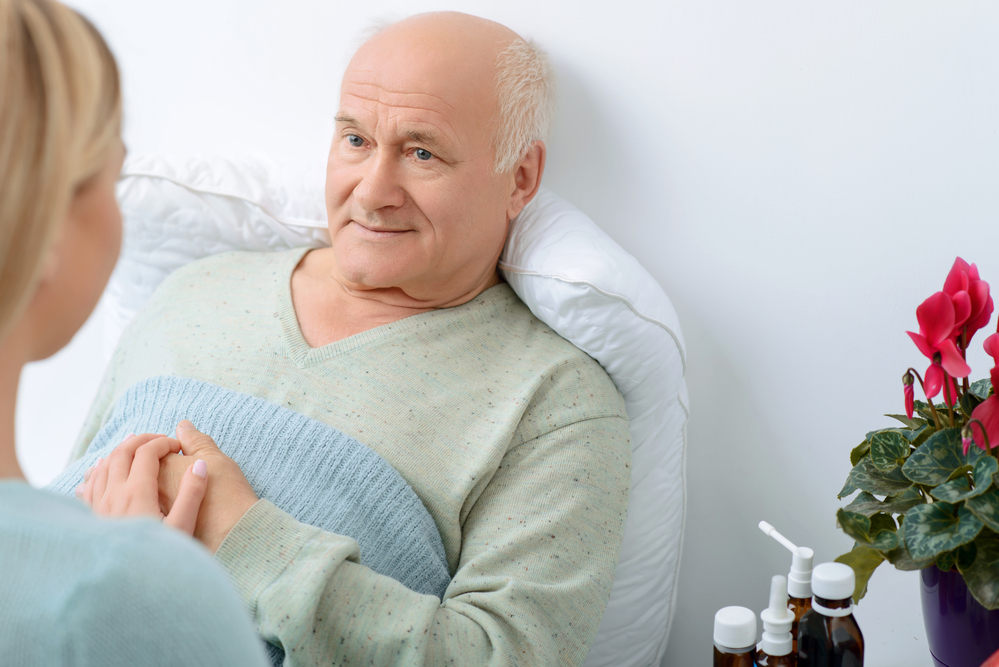 Support is important. Young granddaughter sits beside her grandfather while holding his hand gently and expressing moral support.
